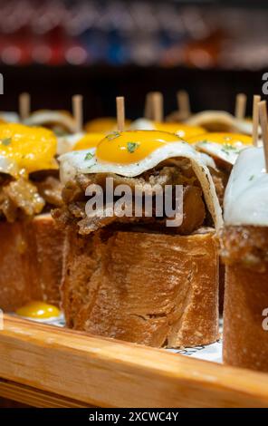 Spuntini tipici dei Paesi Baschi, spiedini di pinchos o pinxtos con piccoli pezzi di pane, pesce, frutti di mare, uova fritte serviti al bar di San Sebastian o. Foto Stock