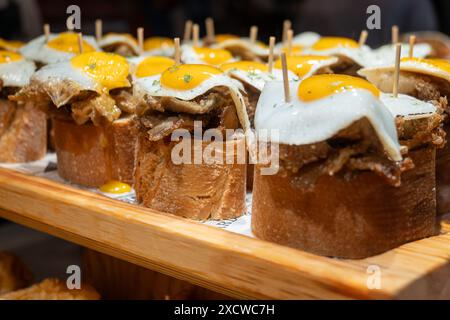Spuntini tipici dei Paesi Baschi, spiedini di pinchos o pinxtos con piccoli pezzi di pane, pesce, frutti di mare, uova fritte serviti al bar di San Sebastian o. Foto Stock
