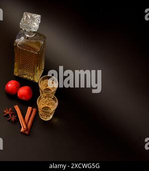 Liquore di prugne con spezie su sfondo nero, alcol forte fatto in casa in un decanter e due bicchieri, frutta matura, bastoncini di cannella e anice. Close-u Foto Stock