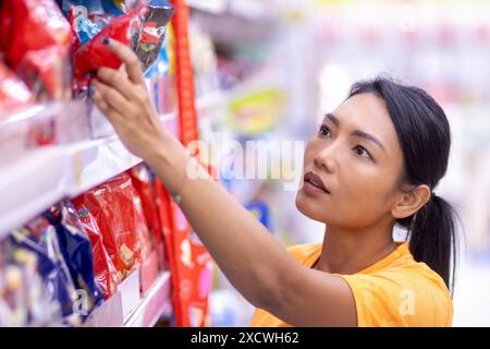 Una donna sceglie i wafer in un supermercato Foto Stock