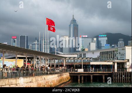 Hong Kong, Cina. 29 aprile 2024. Le bandiere di Hong Kong e della Cina sventolano nel vento al Victoria Harbour e al molo, con grattacieli visibili sullo sfondo. Credito: SOPA Images Limited/Alamy Live News Foto Stock