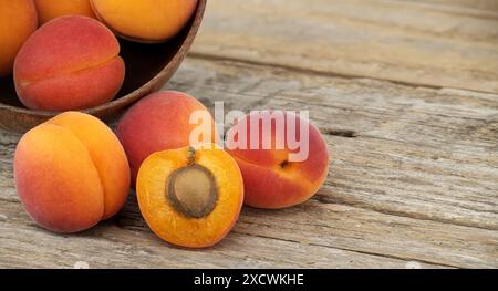 Collezione di albicocche intere mature e un taglio a metà per svelarne l'interno, tavolo rustico in legno Foto Stock