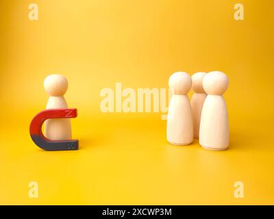 Figure di legno di persone e una calamita. Concetto di gestione del team. Risorse umane. Promuovi. Scegliere un nuovo leader e assumere dipendenti per lavorare. Servizi di caccia alla testa. Licenziamento dei dipendenti. Foto Stock