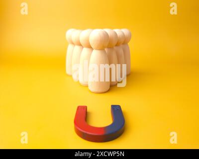 Figure di legno di persone e una calamita. Concetto di gestione del team. Risorse umane. Promuovi. Scegliere un nuovo leader e assumere dipendenti per lavorare. Servizi di caccia alla testa. Licenziamento dei dipendenti. Foto Stock