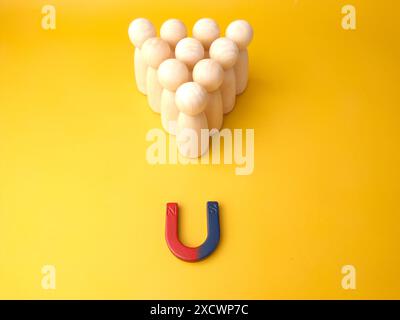 Figure di legno di persone e una calamita. Concetto di gestione del team. Risorse umane. Promuovi. Scegliere un nuovo leader e assumere dipendenti per lavorare. Servizi di caccia alla testa. Licenziamento dei dipendenti. Foto Stock