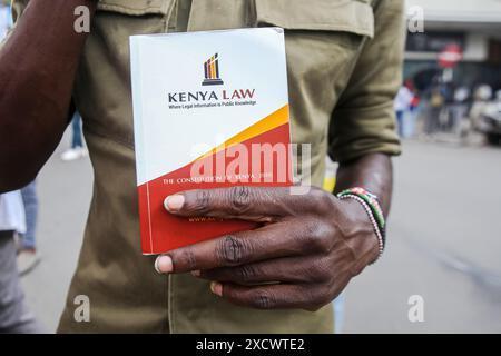 Nairobi, Kenya. 18 giugno 2024. Un manifestante con porta una costituzione keniota prende parte durante una protesta per opporsi a una proposta di legge finanziaria 2024. I manifestanti hanno definito il disegno di legge punitivo a causa delle nuove tasse elevate proposte che vedranno l'aumento del costo della vita che è già elevato. La protesta soprannominata "Occupy Parliament” coincise con la presentazione del progetto di legge al parlamento keniota. La votazione sulla proposta di legge dovrebbe svolgersi il 20 giugno 2024. Credito: SOPA Images Limited/Alamy Live News Foto Stock