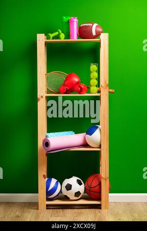 Ripiani con diverse attrezzature sportive contro il muro verde Foto Stock
