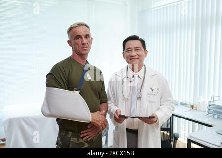 Soldato con braccio ferito che parla con il Dottore Foto Stock