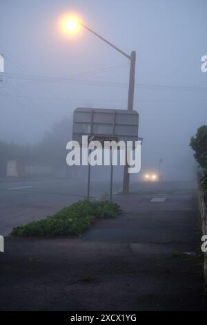 Lampioni, linee elettriche e pali di servizio in una nebbia profonda lungo le strade suburbane di Katoomba Foto Stock