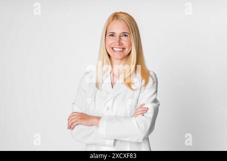 Donna sorridente in bianco camice da laboratorio con braccia incrociate Foto Stock