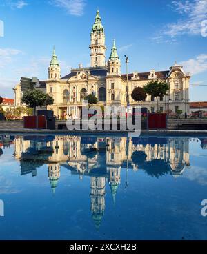 Città ungherese Gyor, municipio con riflessi sull'acqua di notte Foto Stock