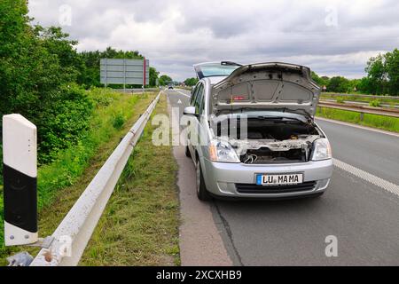 Un'auto in avaria si ferma sull'autostrada con un triangolo di pericolo e pericolo dietro di essa Foto Stock