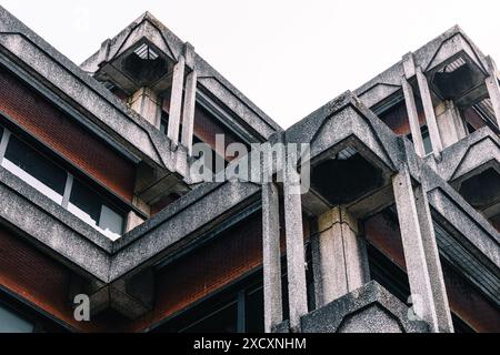 Un primo piano di un edificio dall'architettura brutalista con materiali in cemento e mattoni. Foto Stock
