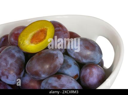 Prugne fresche nel recipiente, fessura, sfondo bianco Foto Stock