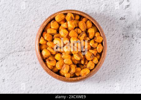 Noci di mais arrosto con salsa in un recipiente di legno su un tavolo in pietra bianca Foto Stock