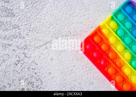 Vista dall'alto del giocattolo sensoriale anti-stress arcobaleno, premi e fallo passare su uno sfondo in pietra Foto Stock