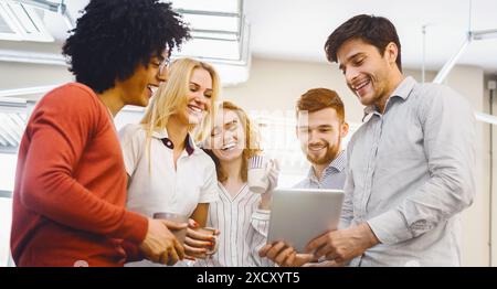 Gruppo di dipendenti intorno a un tablet Foto Stock