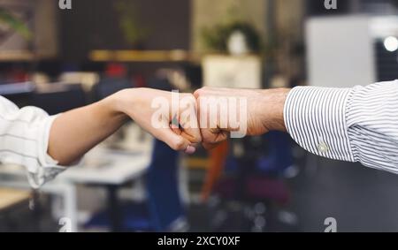 Due persone che si impegnano in Friendly Fist Bump presso l'ufficio interno Foto Stock