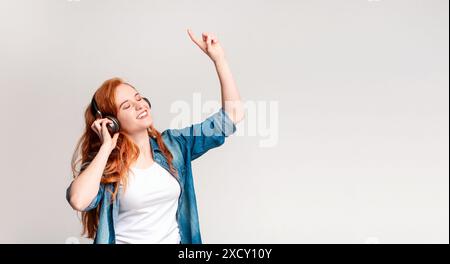 Giovane donna che ama la musica con le cuffie ballando con gioia Foto Stock