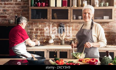 Attiva coppia senior che cucinano insieme nella loro cucina Foto Stock