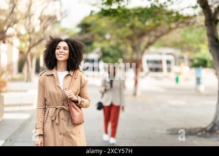 Donna nera sicura di sé imprenditrice che cammina all'aperto in un ambiente urbano Foto Stock