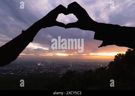 Silhouette coppia mani sollevate per dare forma al cuore su uno splendido sfondo serale. concetto ​​making simbolo del cuore a forma di mano espresso amore f Foto Stock