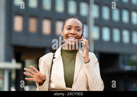 Donna nera sicura di sé imprenditrice che parla al telefono in un ambiente urbano Foto Stock