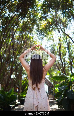 la donna alza le mani e fa del cuore il simbolo dell'amore e dell'amicizia sullo sfondo naturale del bellissimo paesaggio mattutino. Concetto ​​using mani per fare h Foto Stock