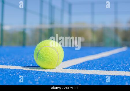 una palla verde sulle linee di un campo da paddle tennis blu Foto Stock