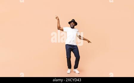 Elegante ragazzo afroamericano che balla su sfondo beige Foto Stock