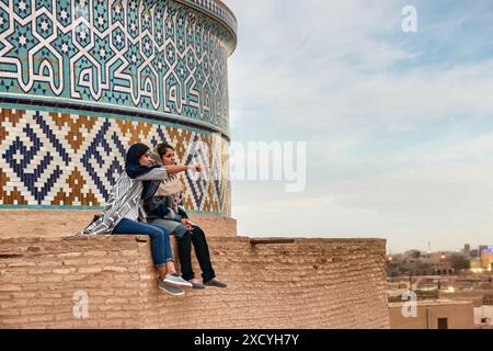 Yazd, Iran - 27 ottobre 2018: Due giovani donne iraniane godono di una vista panoramica dal tetto della Moschea Jameh di Yazd. Foto Stock