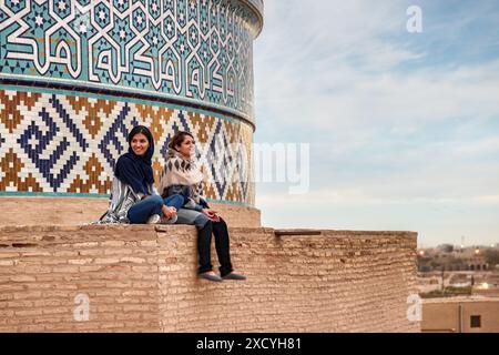 Yazd, Iran - 27 ottobre 2018: Due giovani donne iraniane sorridenti godono di una vista panoramica dal tetto della Moschea Jameh di Yazd. Foto Stock