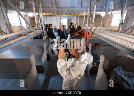 19 giugno 2024, Sassonia, Pödelwitz: Natalie Wiesner del distretto di Lipsia scatta foto al cantiere della chiesa di Pödelwitz. Wiesner è membro del comitato di valutazione per il concorso "il nostro villaggio ha un futuro”, che ha ora visitato il villaggio. Qualche anno fa, il destino del villaggio nell'area mineraria della lignite sembrava sigillato. Pödelwitz doveva essere estratta. La salvezza è arrivata nel 2021. Ora il villaggio sta facendo domanda per il concorso statale organizzato dal Ministero sassone per lo sviluppo regionale. Solo 33 persone vivono ancora nel villaggio, il 80% delle case sono vuote Foto Stock