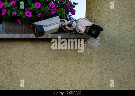 Due telecamere di sicurezza montate sulla parete esterna dell'edificio che monitorano il concetto di sicurezza della sorveglianza dello stato Foto Stock