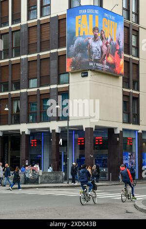 Pannello pubblicitario a LED all'angolo di un edificio nella centrale via della Moscova con pedoni e ciclisti in primavera, Milano, Lombardia, Italia Foto Stock
