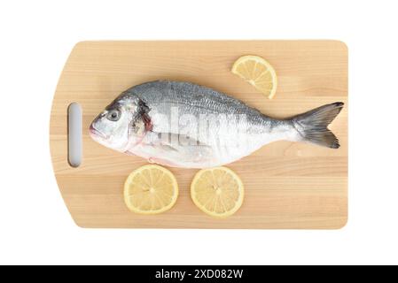 Fette di limone e pesce dorada sbucciato e in camicia su un tagliere di legno. Copia spazio. Foto Stock