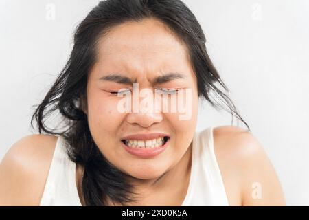 Una donna con una faccia rossa e una coda di cavallo nera. Sta piangendo e ha il mal di denti Foto Stock