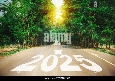 Nuovo anno 2025 o concetto diretto. Testo 2025 scritto sulla strada in mezzo alla strada asfaltata con al tramonto. Concetto di pianificazione, obiettivo, CAL Foto Stock