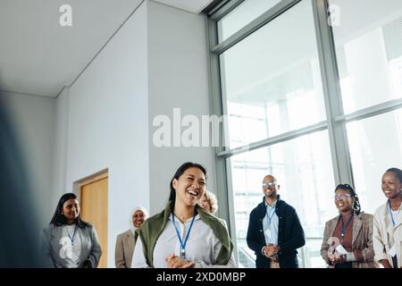 Una donna d'affari sorridente che parla con il suo team durante una vivace conferenza in un ambiente di lavoro moderno. Foto Stock