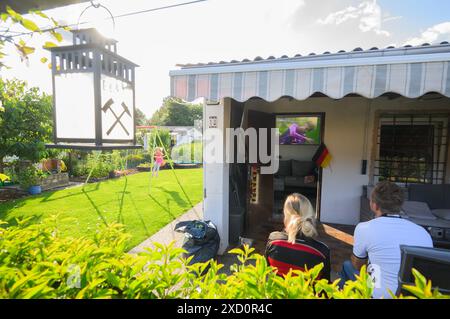 Gelsenkirchen, Germania. 19 giugno 2024. Calcio, UEFA Euro 2024, Germania - Ungheria, turno preliminare, gruppo A, giorno della partita 2. Una famiglia guarda la partita in televisione nel suo giardino di allotment nell'associazione Gelsenpark. Credito: Julian Stratenschulte/dpa/Alamy Live News Foto Stock