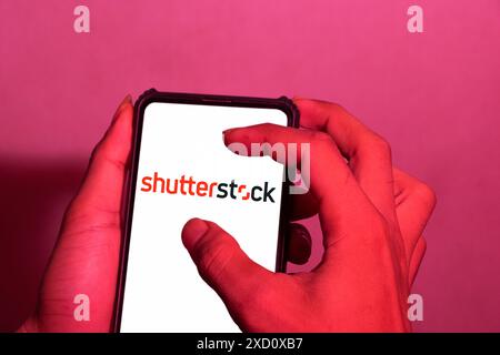 Primo piano di una mano, questa foto mostra il logo della società di fotografia statunitense Shutterstock Inc su uno schermo di un telefono cellulare. tracciato di ritaglio Foto Stock