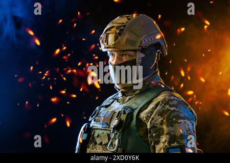 Un ritratto raffigura un soldato in equipaggiamento tattico sullo sfondo di intensi effetti fumo arancione e blu Foto Stock