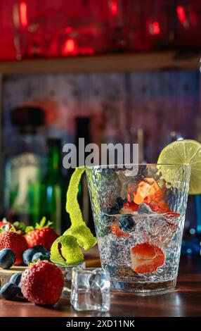 Bere con fragole, mirtilli e lime, serviti in un bicchiere con ghiaccio. Cocktail, rum, vodka, vita notturna, festa e freschezza. Gioia e relax Foto Stock