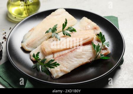 Piatto con merluzzo crudo e prezzemolo su un tavolo leggero, primo piano Foto Stock