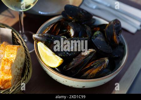 Deliziose cozze al vapore in salsa verde, servite al piatto al tavolo Foto Stock