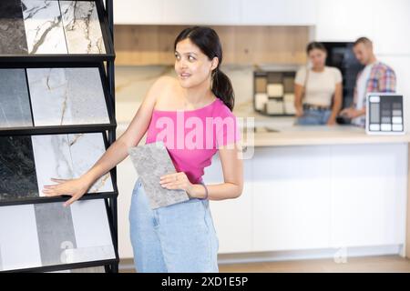 Donna asiatica che sfoglia campioni di piastrelle nel negozio di articoli per la casa Foto Stock