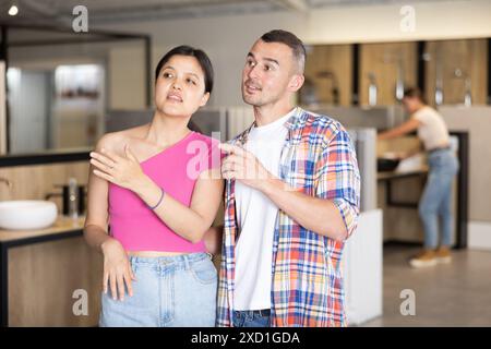 Una simpatica coppia interrazziale in cerca di accessori per il bagno nello showroom Foto Stock