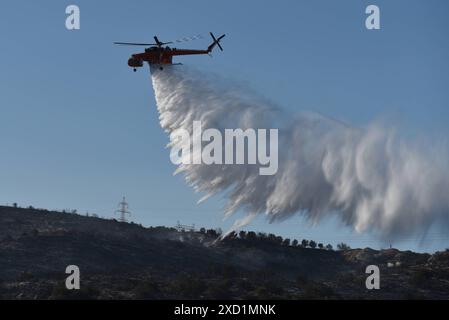 Scoppia un incendio a Koropi, vicino ad Atene, Un elicottero antincendio rilascia acqua per estinguere l'incendio a Koropi, vicino ad Atene. Atene Grecia Copyright: XNicolasxKoutsokostasxNicolasxKoutsokostasx DSC 202406190805 Foto Stock