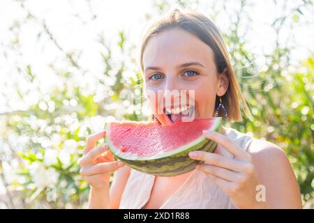 Una giovane rossa sta mangiando un anguria durante l'estate. Foto Stock