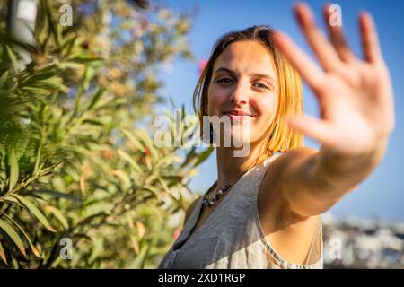 Una donna con i capelli biondi e una collana sorride e saluta. Immagine con un umore felice e amichevole. Foto Stock